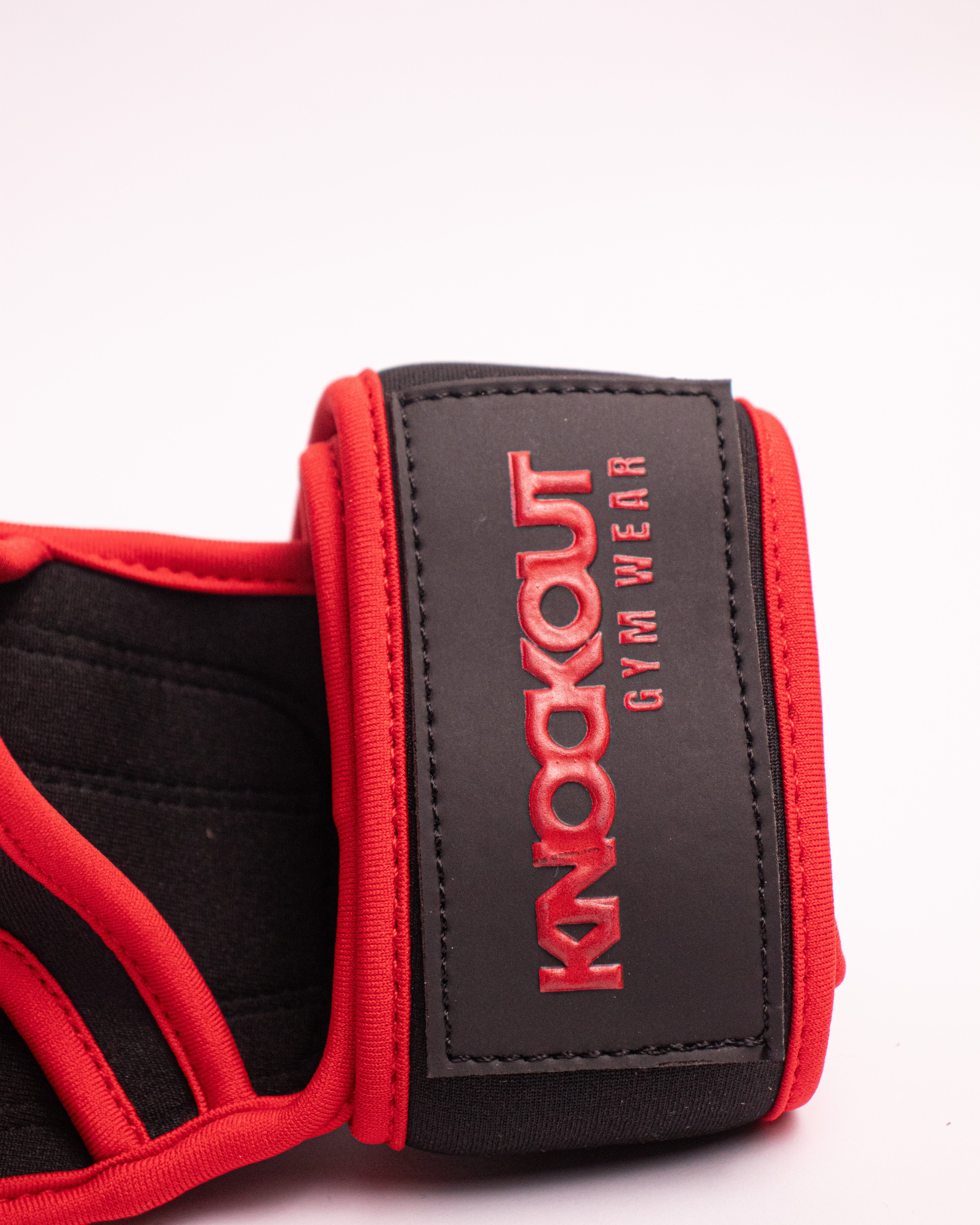 Red and black gym wrist wrap with 'Knockout Gym Wear' branding on a white background